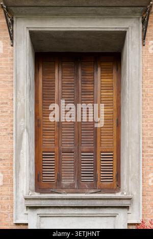 Vintage Wooden Window Shutters Set in Brick Wall With Concrete Frame and Rustic Charm Stock Photo
