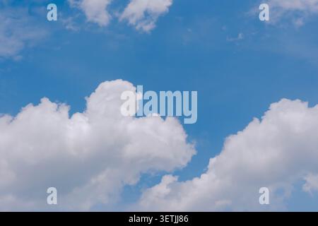 Soft white clouds float across a bright blue sky, creating a calm, airy background with plenty of copy space for weather, travel, summer, or nature th Stock Photo