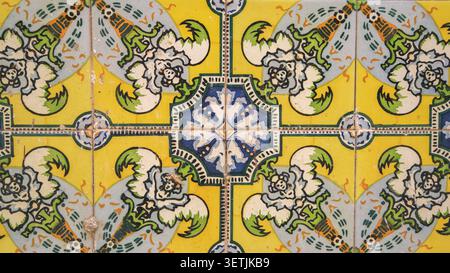 A close-up view of vintage hand-painted ceramic tiles featuring colorful floral and geometric motifs, creating a nostalgic and elegant decorative wall Stock Photo