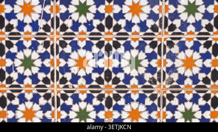 A detailed close-up of intricate, hand-painted ceramic tiles featuring colorful geometric star patterns in a classic Middle Eastern architectural styl Stock Photo