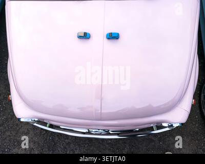 Top view of a pink fiat 500 from italy with two blue model fiat 500 toys on the front Stock Photo