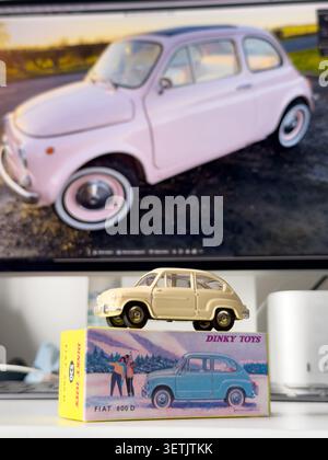 Dinky Toys diecast model of a Fiat 600D on its product packaging box in front of a computer monitor displaying a pink Fiat 500 Stock Photo