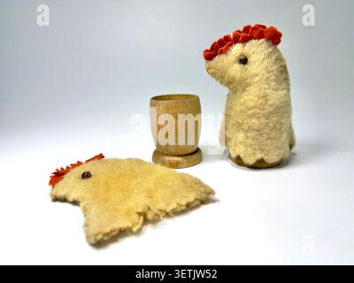 Vintage handmade felt chicken egg warmers & wooden egg cup on a plain white background egg cosy Stock Photo