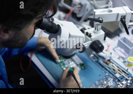 Technician repairing circuit board under microscope Stock Photo
