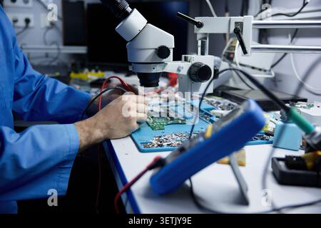 Man is repairing on electronic repair workbench equipped with circuit board Stock Photo
