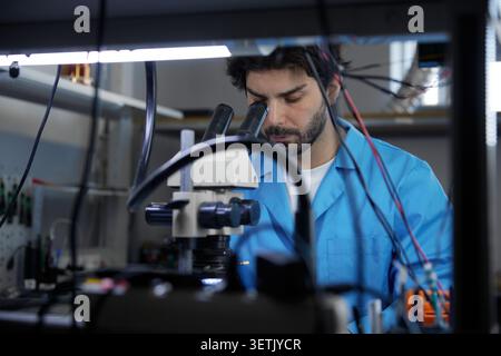A dedicated scientist is diligently working in a laboratory using a microscope for research Stock Photo
