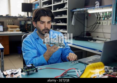 A man worker is wearing a blue shirt holding a motherboard in his hands Stock Photo