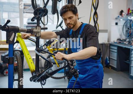 Skilled worker calibrating bicycle brake cable in workshop Stock Photo