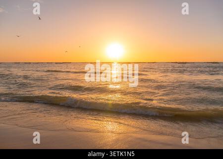 Golden sunset illuminates Atlantic Ocean waves rolling onto sandy beach near Nouakchott in Mauritania. Stock Photo