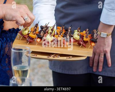 Freshly grilled shrimp served as gourmet appetizers during a catered cocktail reception in France, with chefs preparing and serving the seafood live. Stock Photo