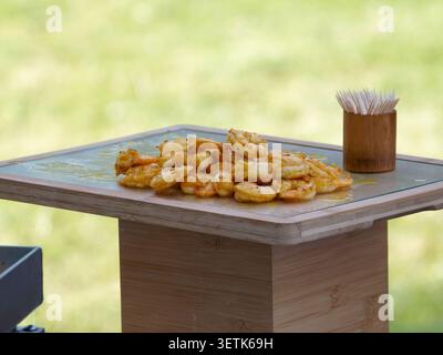 Freshly grilled shrimp served as gourmet appetizers during a catered cocktail reception in France, with chefs preparing and serving the seafood live. Stock Photo