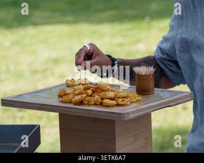 Freshly grilled shrimp served as gourmet appetizers during a catered cocktail reception in France, with chefs preparing and serving the seafood live. Stock Photo