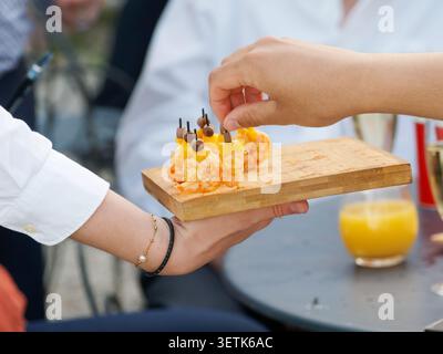 Freshly grilled shrimp served as gourmet appetizers during a catered cocktail reception in France, with chefs preparing and serving the seafood live. Stock Photo