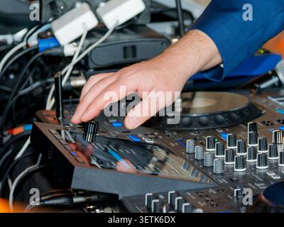 Close-up of a DJ adjusting a professional mixing console during a live event or wedding reception in France. Stock Photo