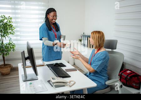Diverse healthcare workers enjoying a coffee break in a modern hospital setting Stock Photo