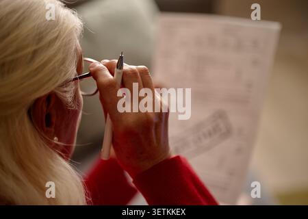 Senior Woman Reviewing Documents and Taking Notes at Home Stock Photo