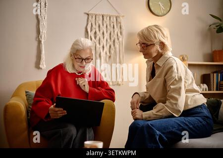 Senior Woman Using Laptop with Middle Aged Woman at Home Stock Photo