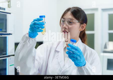A young female scientist examines test tubes in a lab showcasing the intersection of technology and research in scientific study. Stock Photo
