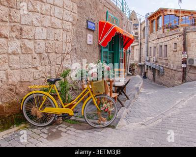 CAPPADOCIA, TURKEY - APRIL 23, 2026: A decorative yellow bicycle with a flower basket parked on a cobblestone street in front of a stone building in t Stock Photo