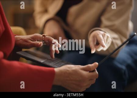 Senior Woman Using Laptop with Caregiver Supporting Digital Access Stock Photo