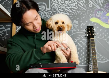 Casual guy and his furry friend make tunes in a lively recording studio. Stock Photo