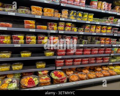 A variety of fresh cut fruits packaged in clear plastic trays on shelves within a supermarket. Texas, USA. Stock Photo