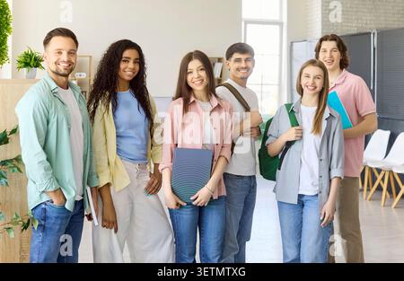 Diverse group of smiling college students standing in classroom, learning together Stock Photo