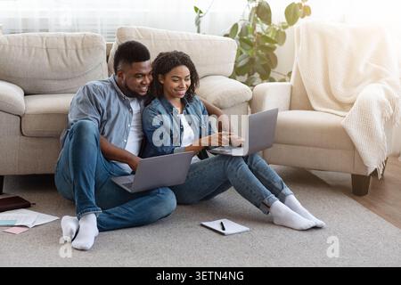 Remote Work. Black Couple Using Laptops At Home, Working Online Together Stock Photo