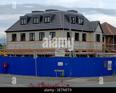 Building under refurbishment on Alderley Road in North West England, UK, with scaffolding and blue construction hoardings. Stock Photo