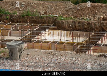 Close-up view of a building construction site featuring steel reinforcement grids, wooden formwork boards, and structural elements under development. Stock Photo