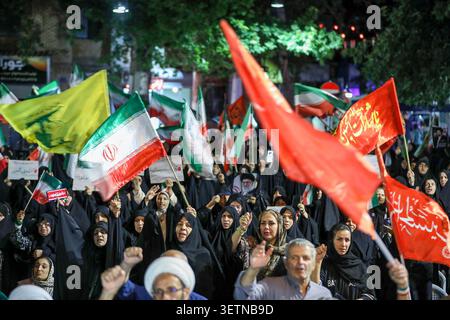 June 23, 2026, Tehran, Iran: Supporters wave Iranian national flags alongside Hezbollah and religious flags during a state-organized rally in Iran. The rally followed the June 18 signing of an interim memorandum of understanding by U.S. President Donald Trump and Iranian President Masoud Pezeshkian, aimed at ending the regional conflict that began with U.S.-Israeli strikes on Iran on February 28. On June 22, Washington temporarily eased sanctions on Iranian oil exports after U.S. Vice President JD Vance said Tehran had agreed to invite International Atomic Energy Agency inspectors back into th Stock Photo