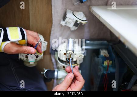 Close-up of dishwasher motor and pump repair, showcasing technical work, troubleshooting and household appliance servicing. Stock Photo