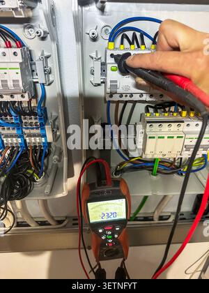 Measuring voltage with multimeter in electrical panel Stock Photo