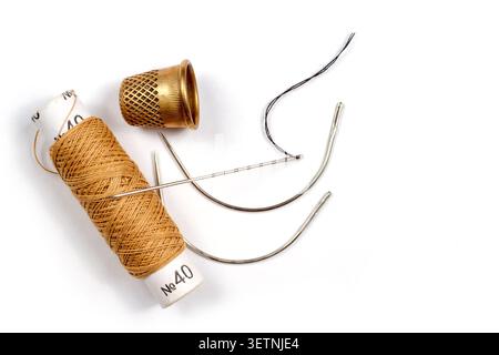Composition of threads of needles and a thimble on a white background. Close-up sewing supplies. Stock Photo