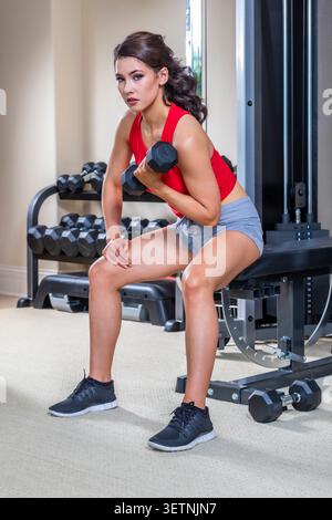 A young woman trains in her home gym, focused and energized, performing exercises with determination and strength, setting a powerful tone for her day Stock Photo