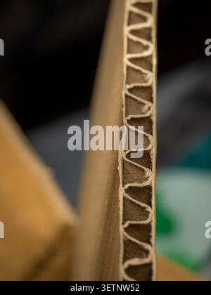 Macro selective focus of the vertical cut edge of a brown corrugated cardboard sheet showing the internal wavy fluting layer pattern texture Stock Photo
