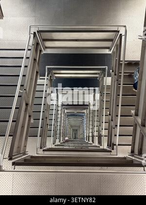 A top-down view of a repetitive industrial steel staircase featuring diamond plate treads inside the BALTIC Centre for Contemporary Art. Stock Photo