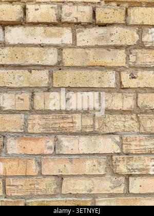 Background of Old Yellow Brick Wall with Weathered Blocks in Vertical Orientation. Stock Photo