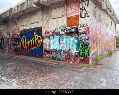 Exterior of a brick building featuring multi-colored spray paint graffiti and street art in Newcastle upon Tyne, England. Stock Photo
