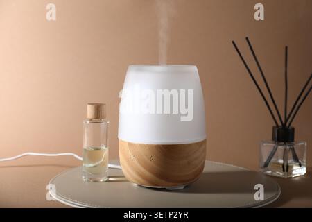 Aromatherapy. Aroma lamp, essential oil and reed freshener on dark beige background Stock Photo