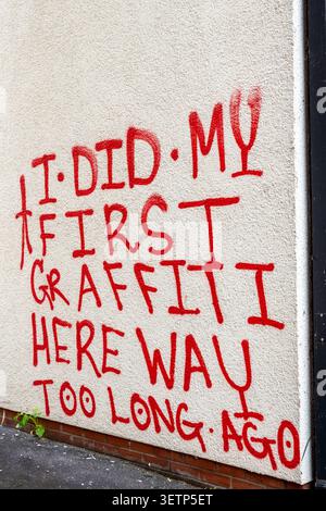 Graffiti in Bristol of red script saying 'I did my first graffiti here way too long ago" in red on a cream coloured wall. Stock Photo