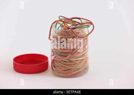 Colorful Rubber Bands in Clear Jar With Red Lid on White Background - Office Supplies Stock Photo
