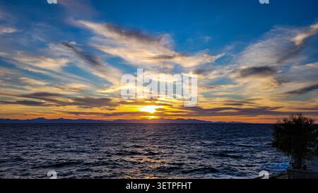 Dramatic sunset over the Mediterranean sea with the sun setting behind Corsica. Stock Photo