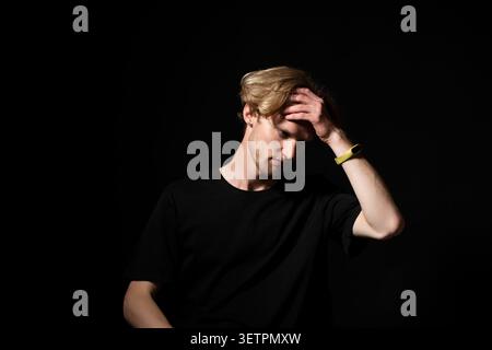 Young man feeling stressed and overwhelmed, suffering from headache or mental fatigue while contemplating a problem or difficult decision, isolated Stock Photo
