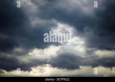Dark dramatic storm clouds covering the sky before heavy rain. Moody weather background with copy space for climate and forecast concepts. Stock Photo