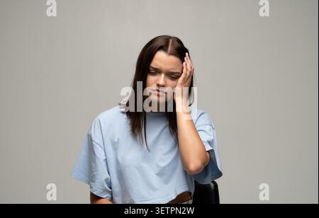 Young woman suffering from headache with hand on temple showing physical discomfort and emotional stress Stock Photo