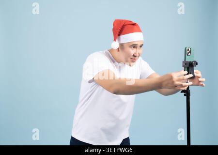 Man in Santa hat standing and gesturing actively near standard stand Stock Photo