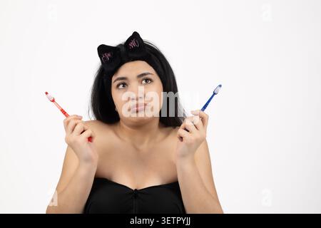 Young woman with cat ears holding two cosmetic brushes on white background Stock Photo