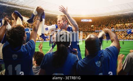 Back view of fan leader standing with megaphone in packed soccer arena, chanting. Rear view of fans in stadium singing behind shouting football supporter Stock Photo