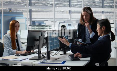 Engineering team doing semiconductors prototyping with artificial intelligence in office. Diverse coworkers brainstorming technical innovations in microchip factory RD lab with AI model, camera A Stock Photo